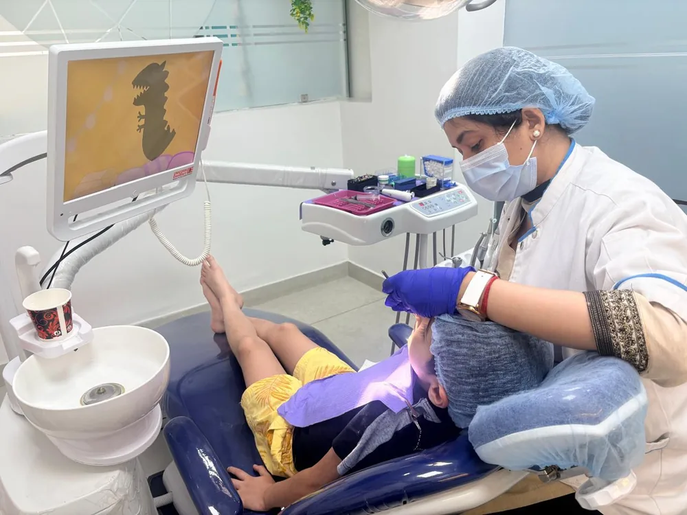 Dentist gently treating a young patient while a cartoon plays on the chair-side screen at Imperial Dental